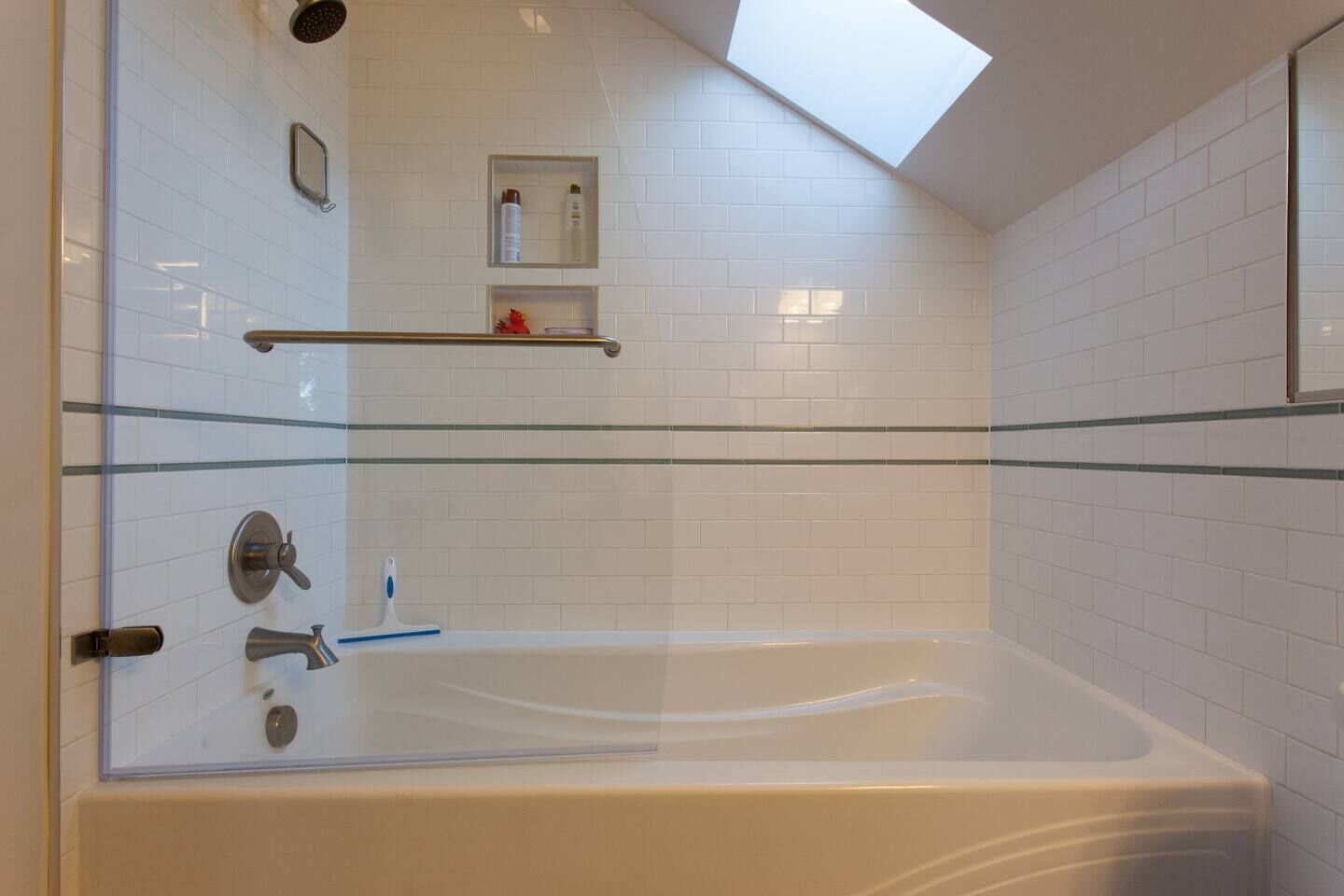 A modern bathroom with a glass-enclosed bathtub, a skylight, and a shower area.