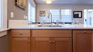 A modern kitchen with a large island, stainless steel sink, and pendant lighting. - Cozy Private Cottage Near Downtown Portland (Portland)