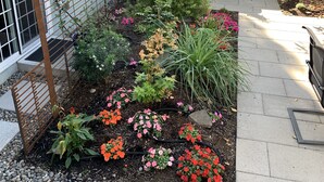 Ein Garten mit Terrasse und Gartenmöbeln, umgeben von einem Holzzaun.
