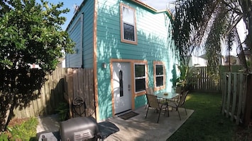 Patio with table, chairs, shade umbrella, grill and hose to rinse off the sand