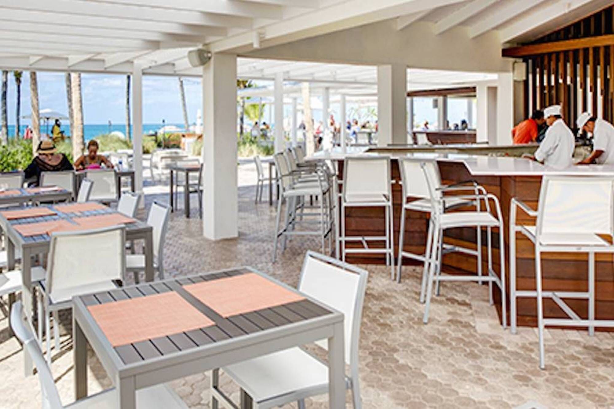 Un'area esterna con tavoli e sedie, una zona bar e vista sull'oceano.