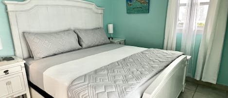 A bedroom with a bed, nightstand, and a painting on the wall.