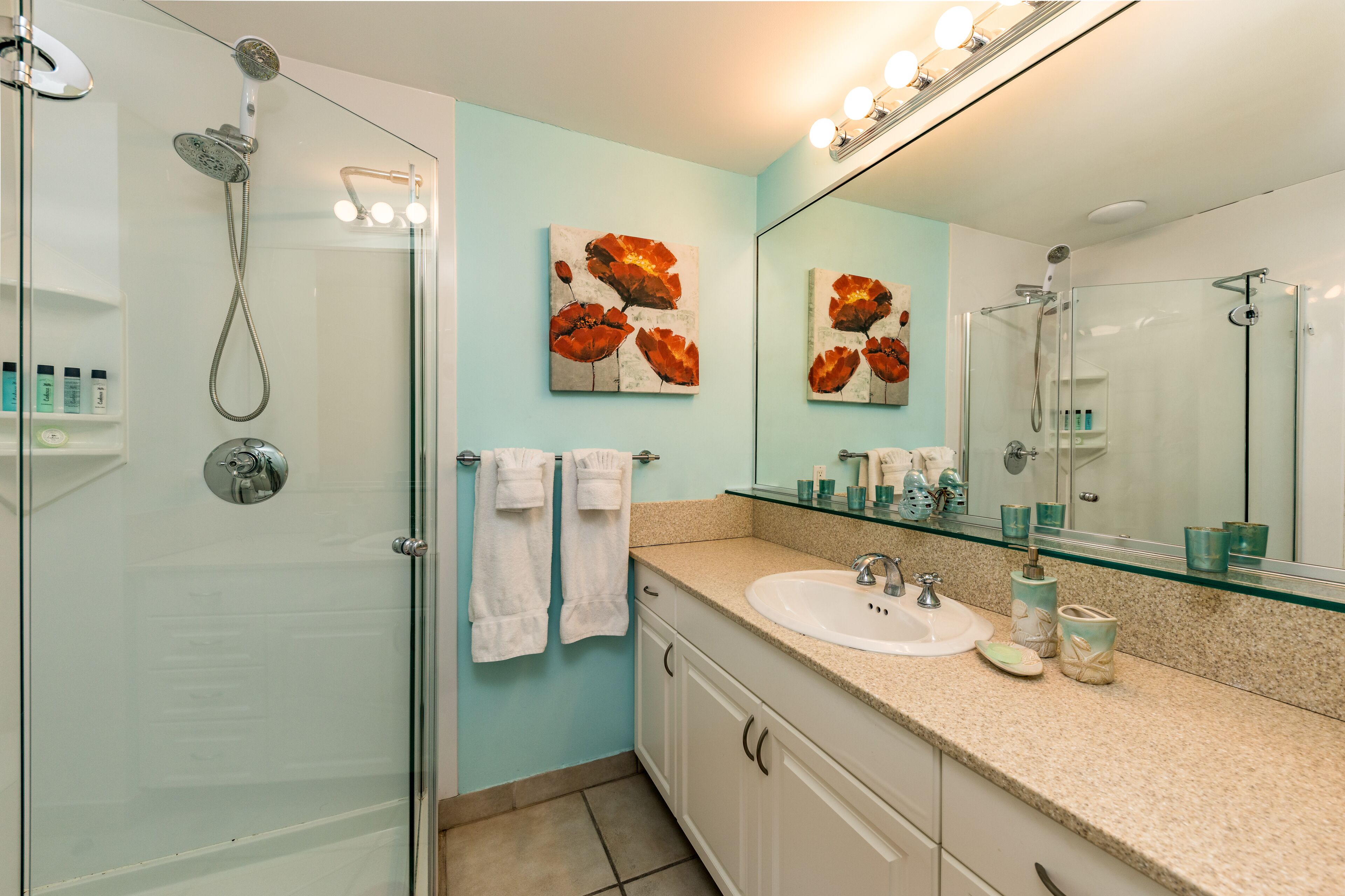 A modern bathroom with a glass shower enclosure, a white sink, and two wall-mounted mirrors.