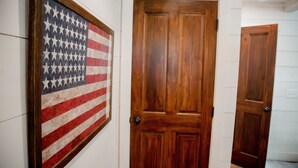 A hallway with a framed American flag and wooden doors. - Walk to DT Highlands | Designer Cabin | Fireplace | Fenced Yard | Dog Friendly (Highlands)