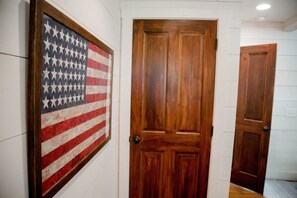 A hallway with a framed American flag and wooden doors. - Walk to DT Highlands | Designer Cabin | Fireplace | Fenced Yard | Dog Friendly (Highlands)