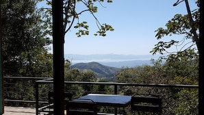 A table and chairs on a balcony overlooking a mountainous landscape with a clear sky. - Above the Gulf House: Spectacular Ocean View! (Monteverde)