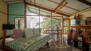 A room with a bed, wooden furniture, and a TV. - Above the Gulf House: Spectacular Ocean View! (Monteverde)