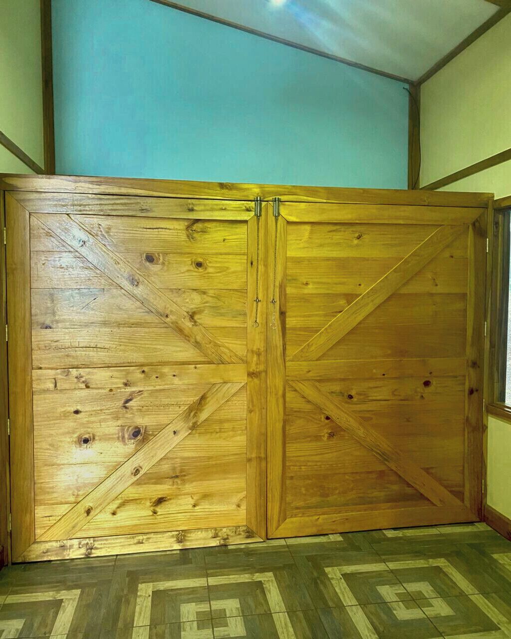 Una puerta corredera de madera con un diseño geométrico, suelo de baldosas y una pared lisa.