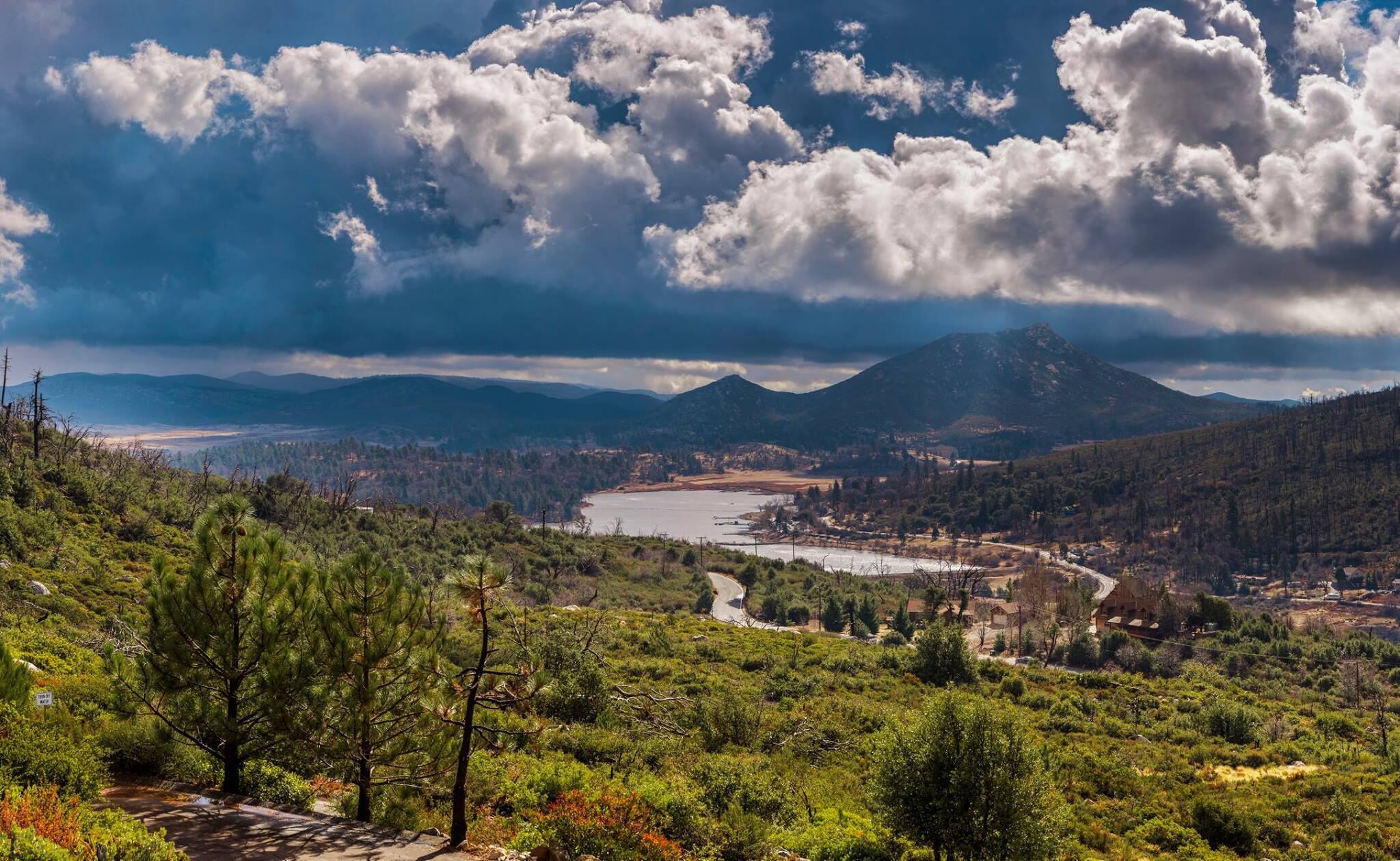 A mountainous landscape with a river, a winding road, and a small settlement.