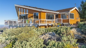 A modern house with a balcony, large windows, and a view of the surrounding landscape.