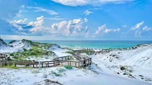 A sandy beach with a wooden boardwalk leading to the water, surrounded by dunes. - Direct Gulffront! BREATHTAKING 270 degree Ocean Views! Large 2600 sqft 3bdrm! (WaterSound Beach)
