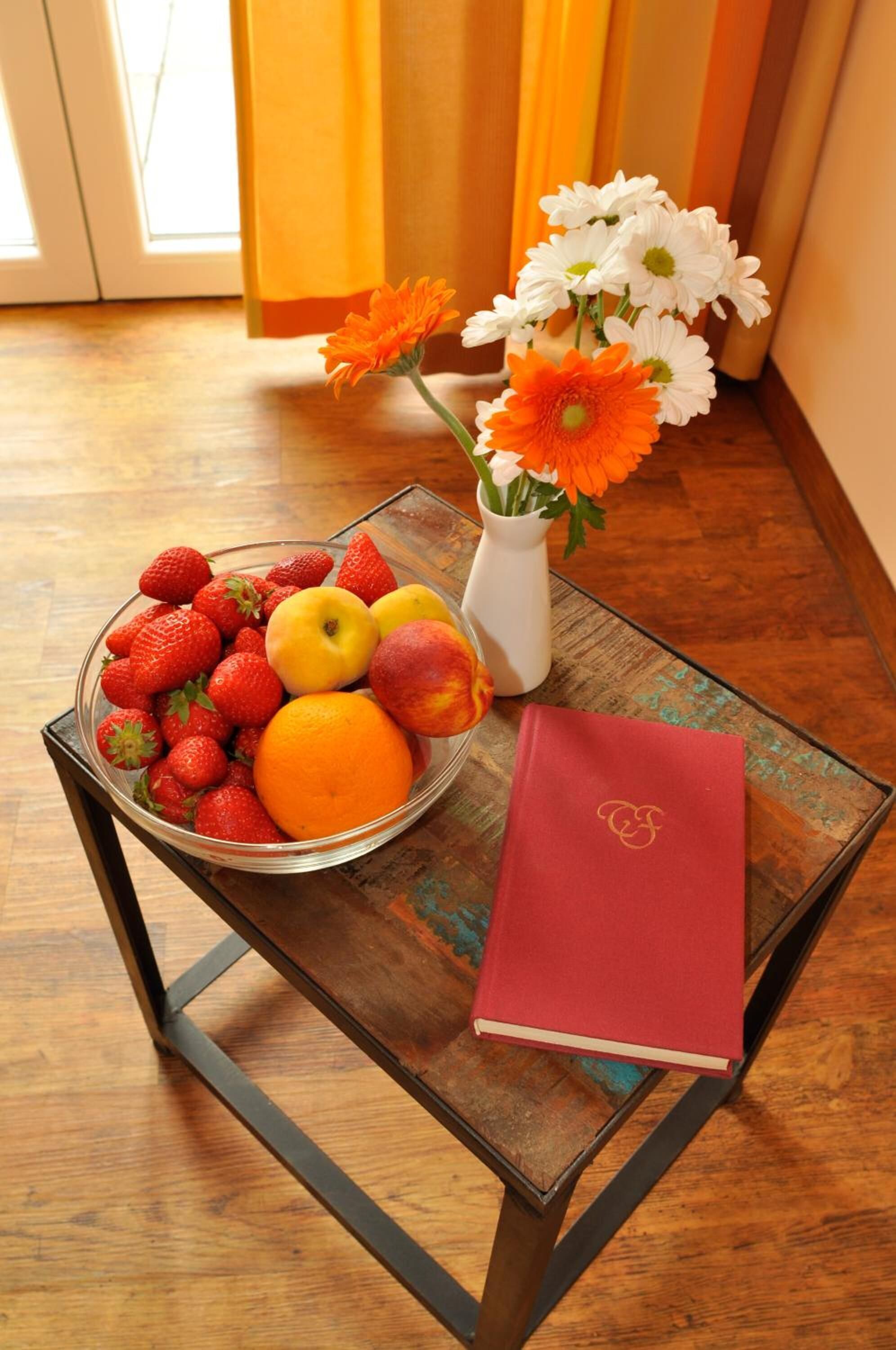 Een tafel met een fruitschaal, een vaas met bloemen en een boek.