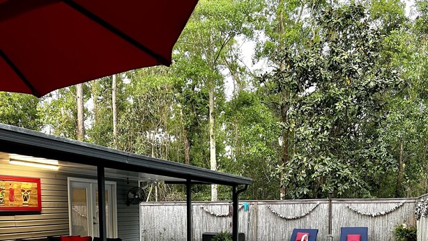 Quintal com piscina, móveis para área externa e varanda coberta.