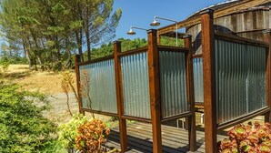 Eine Holzterrasse mit Metall-Blickschutz, einer Duschkabine und Blumentöpfen.