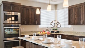A modern kitchen with dark wood cabinets, stainless steel appliances, and a central island with seating. - PVZ102| Steps to Waterpark * Pool * Pvt Hot Tub (Santa Clara)