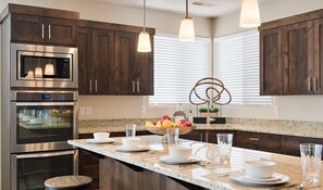 A modern kitchen with dark wood cabinets, stainless steel appliances, and a central island with seating.