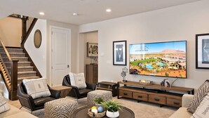 A modern living room with a staircase, a large flat-screen TV, and a comfortable seating area. - PVZ102| Steps to Waterpark * Pool * Pvt Hot Tub (Santa Clara)