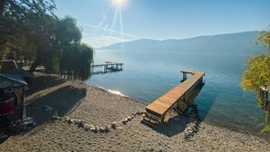 A lakeside scene with wooden docks extending into calm water, surrounded by trees and a clear sky.