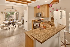Una cocina moderna con armarios de madera, una isla central y luces rosas colgantes.