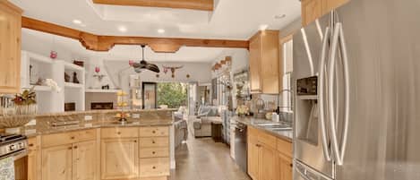 A spacious kitchen with wooden cabinets, a large stainless steel refrigerator, and a central island.