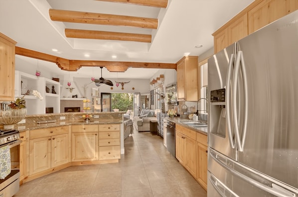Una cocina amplia con armarios de madera, un refrigerador de acero inoxidable grande y una isla central.