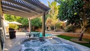 Uma banheira de hidromassagem com área de pátio, piscina e mobiliário de exterior.