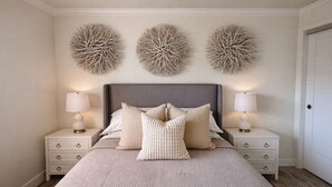 A bedroom with a large bed, two bedside tables, and three wall-mounted spherical decorations. - Modern Barefoot Beach 2BR Condo, Steps to Beach & Pool (Indian Shores)