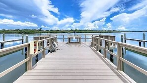 A wooden pier extending over calm water, with a clear sky above. - Modern Barefoot Beach 2BR Condo, Steps to Beach & Pool (Indian Shores)