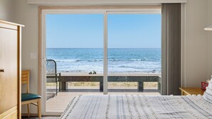 Habitación de hotel con un amplio ventanal corredero que da a una vista de la playa.