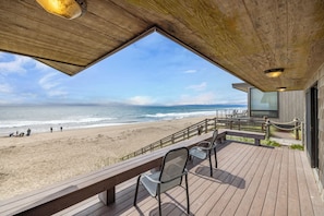 Eine Holzterrasse mit Blick auf Strand und Meer.