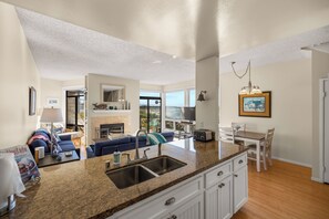A modern kitchen with granite countertops, a built-in sink, and a dining area with a table and chairs.