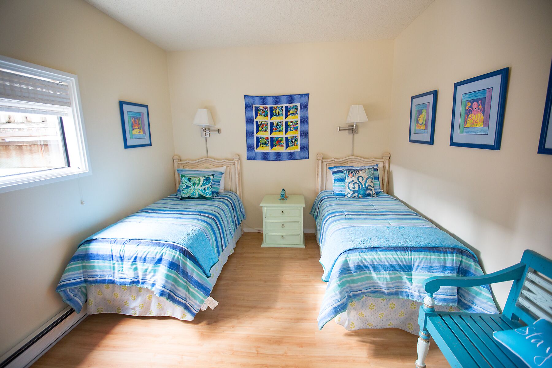 A bedroom with two beds, a nightstand, a chair, and a window.