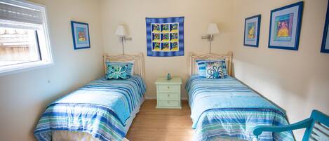 A bedroom with two beds, a nightstand, a chair, and a window.