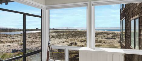 A room with large windows offering a view of a beach and distant mountains.