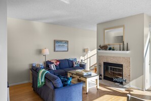 A living room with a sofa, a coffee table, a fireplace, and a mirror on the wall.