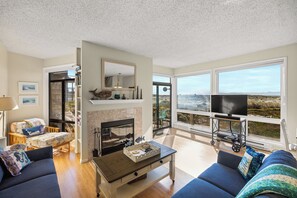 A living room with a fireplace, a television, and a view of the outdoors.