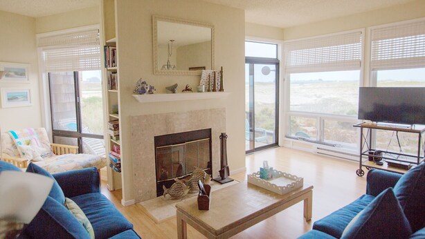 Een woonkamer met een open haard, een televisie en een groot raam met uitzicht.