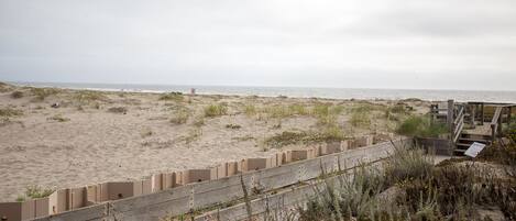 A beach with a wooden fence and a boardwalk leading to the water.