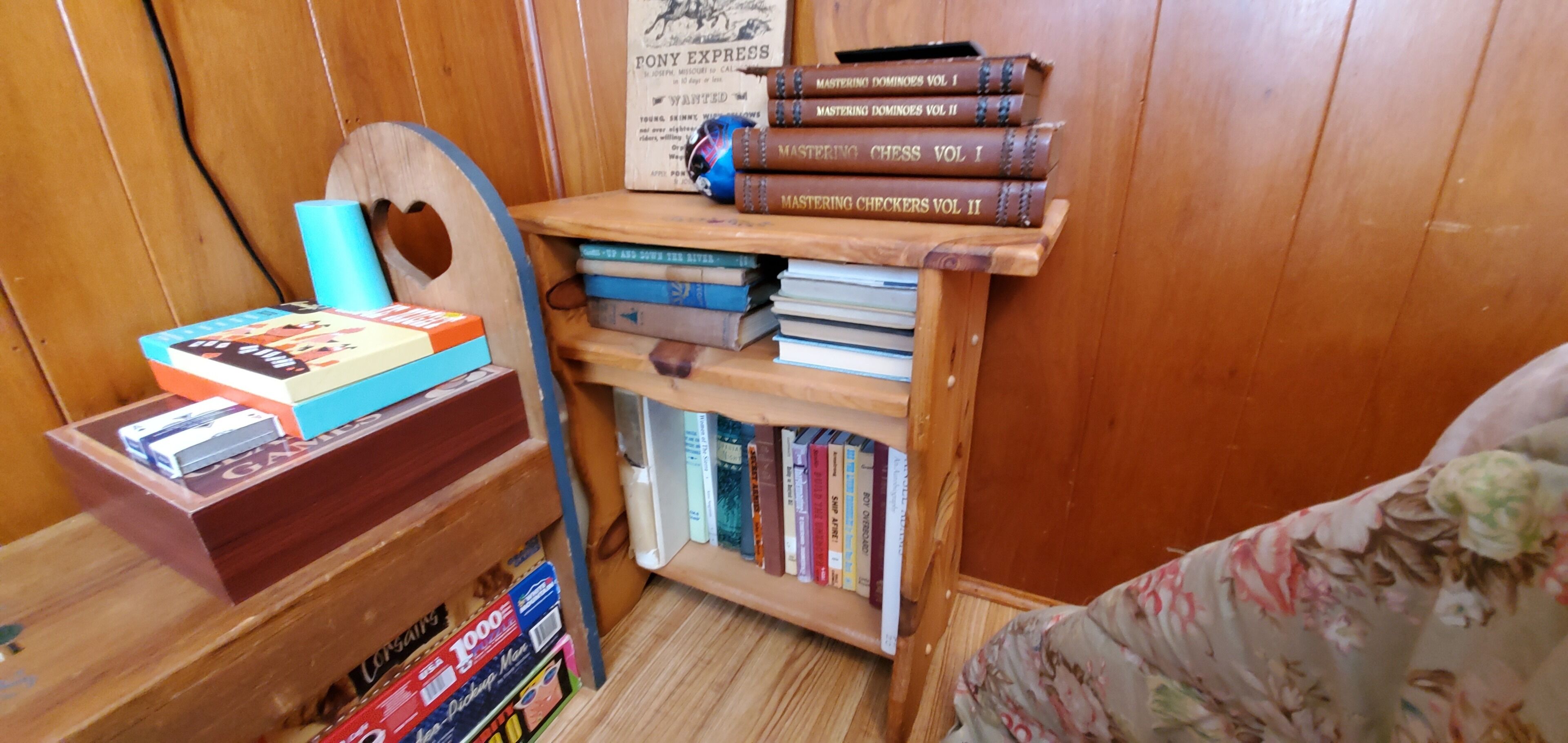 A wooden bookshelf with books and board games.
