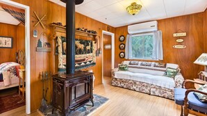 A cozy room with a wooden interior, a fireplace, a sofa, and a bed.