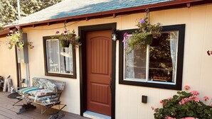 A wooden deck with a bench, a door, and hanging flower baskets.