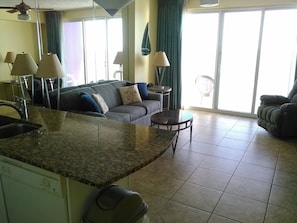 A spacious living area with a kitchen island, a sofa, and a dining table. - Ocean Walk Resort 1502 Spectacular View (Daytona Beach)
