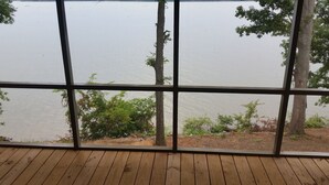 A wooden deck with a view of a calm lake and trees. - Bridgeview Cottage with Weekday Pontoon Boat Access, and Quiet Peninsula Setting (Cadiz)