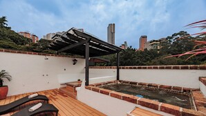 Terraza en la azotea con hidromasaje, sillas de descanso y una pérgola.