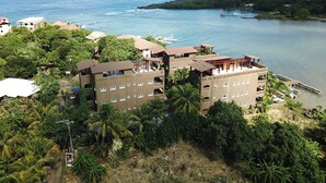 A coastal hotel with multiple floors, balconies, and a view of the sea. - Luxury Waterfront Condo w/ Pool,  Dock, and Gardens  (West End)