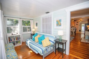 A bedroom with a bed, a nightstand, a bookshelf, and a view of the dining area.