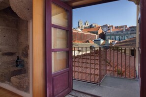 A balcony with a view of traditional buildings and a stone wall.