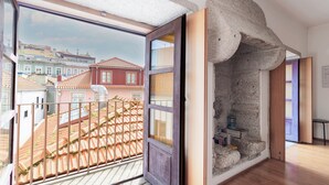 Een kamer met een groot raam, een stenen muur en uitzicht op gebouwen.