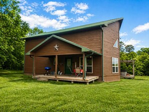 A wooden cabin with a porch, a star decoration, and a grill outside.