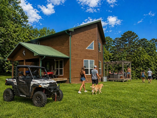 A wooden cabin with a covered porch, a patio area, and a grill station.
